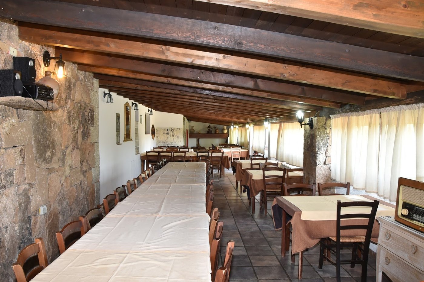 Sala del ristorante dell'agriturismo a Monti con travi in legno e tavoli apparecchiati